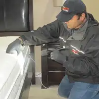 Bed bug inspection technician checking a mattress and bed frame for signs of infestation in Atlanta, GA