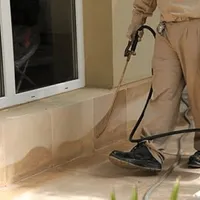 General pest control technician spraying exterior perimeter around a home in Atlanta, GA