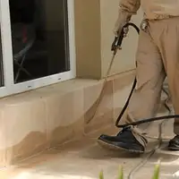 General pest control technician spraying exterior perimeter around a home in Atlanta, GA