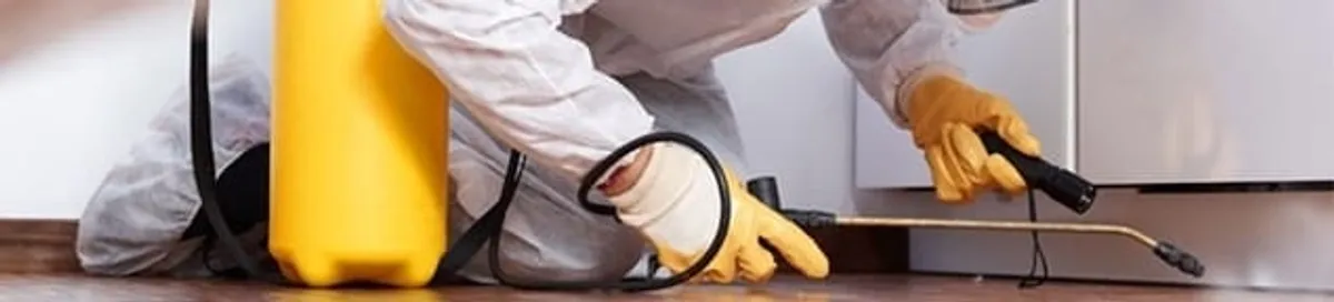 Roach exterminator treating cracks and crevices along kitchen baseboards in Atlanta, GA