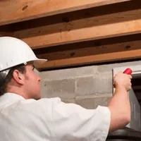 Termite inspection technician checking a basement wall and framing for termite activity in Atlanta, GA