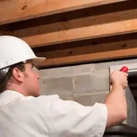 Termite inspection technician checking a basement wall and framing for termite activity in Atlanta, GA
